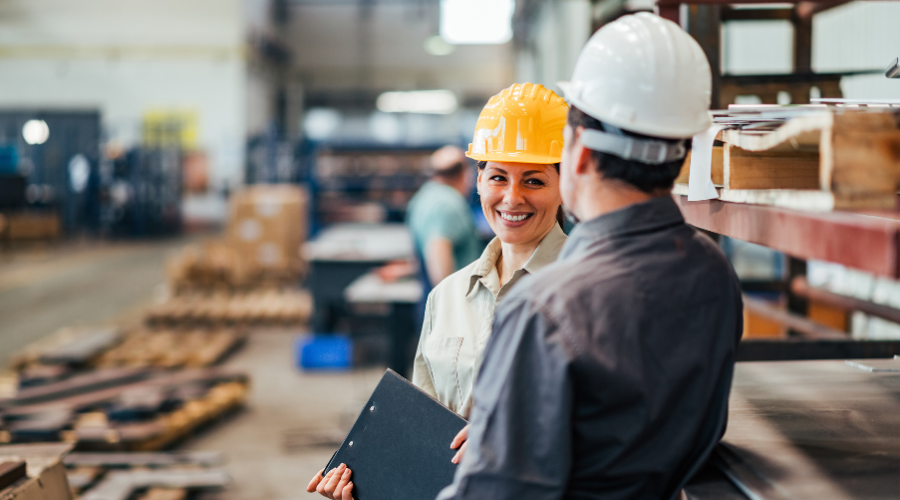 two workers talking in a factory.