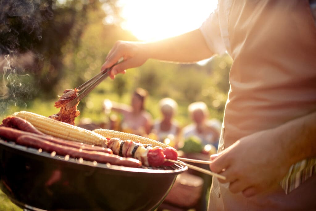Man preparing food on garden barbecue.