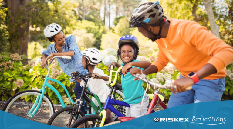 a Family on their bikes in the park all with happy smiling faces.