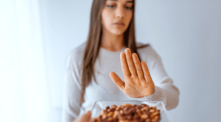 Lady with her hand up to avoid a plate of nuts.