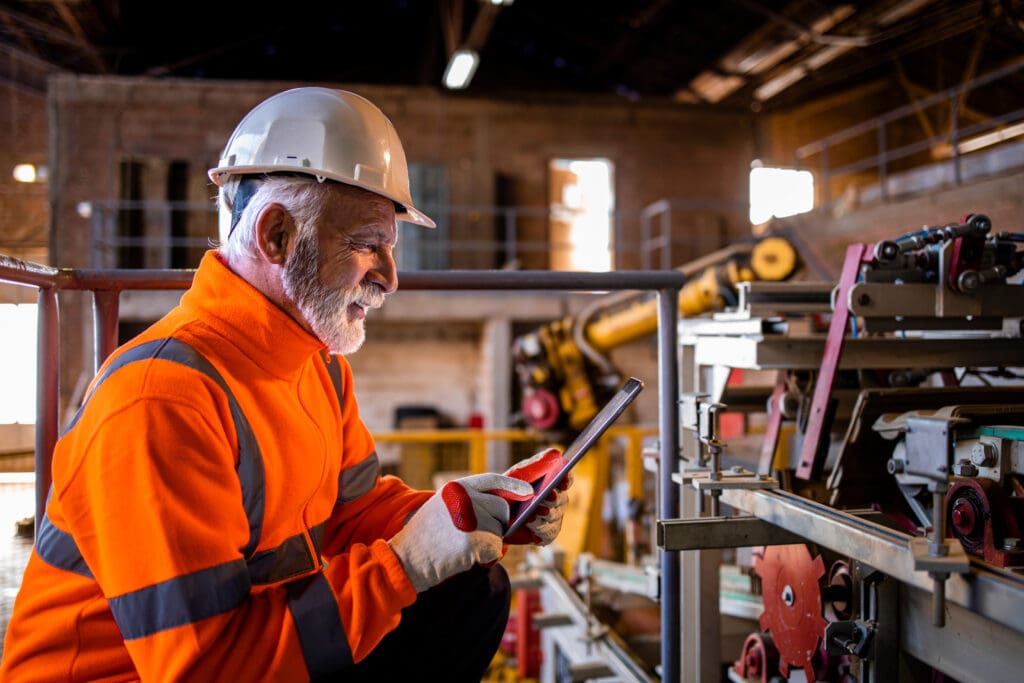 Industrial engineer or technician wearing safety equipment using a tablet.