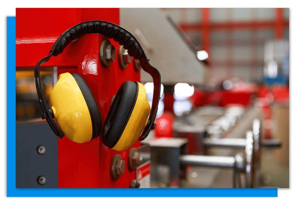 Yellow ear defenders resting on red metal racking in a warehouse.