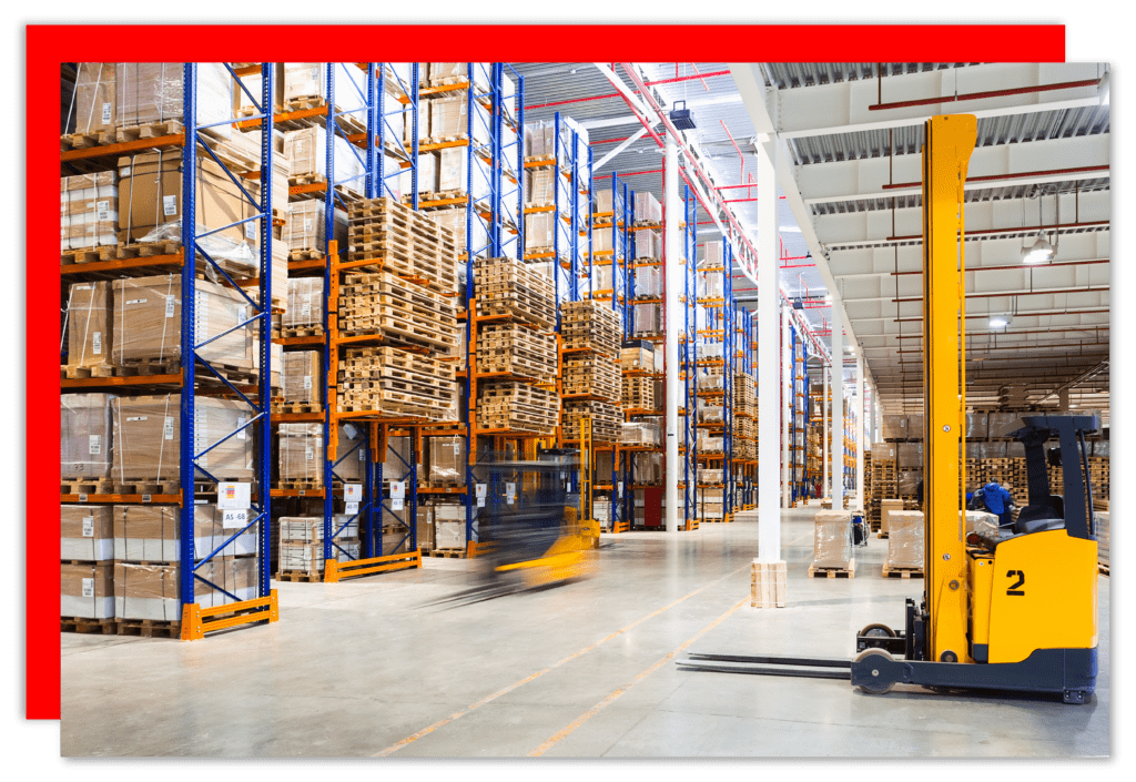 A warehouse with floor to ceiling racking and two yellow forklifts.