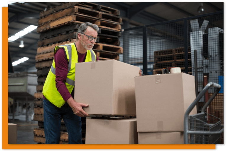 Worker in a hi vis vest carrying a box in a warehouse.