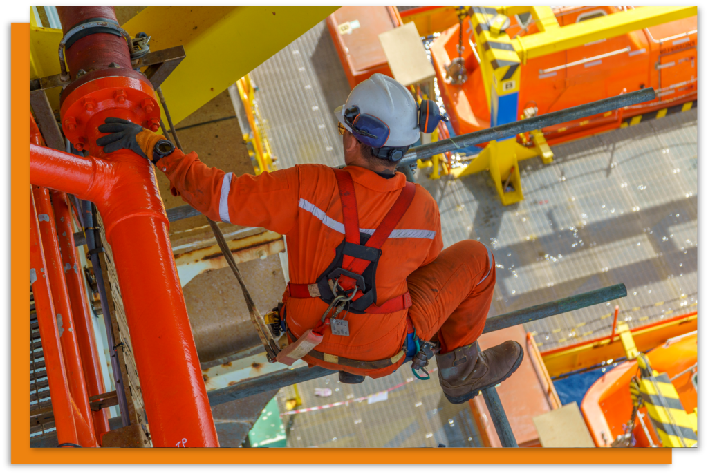 A worker on scaffolding in a hi vis suit with a white hard hat.