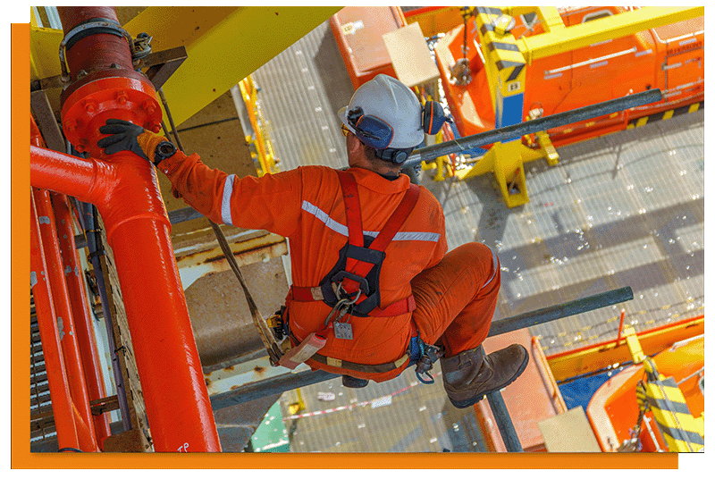 A worker on scaffolding in a hi vis suit with a white hard hat.