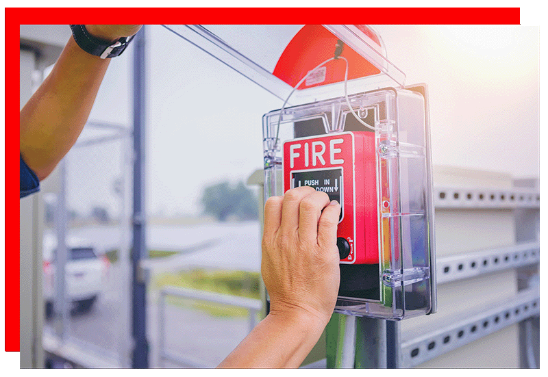 A raised hand ready to pull on a fire alarm hande.