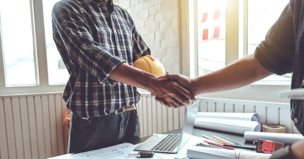 Two workers shaking hands in an office.