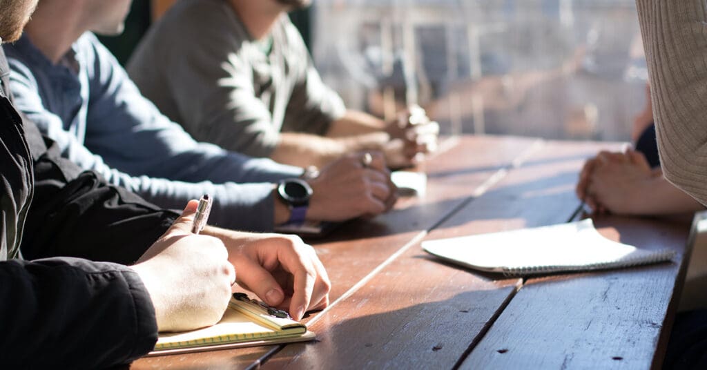 A group of people writing notes on notepads at a table.