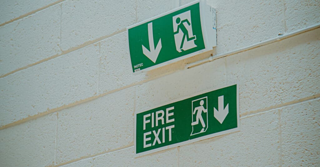 Green fire exit sign on a white wall.
