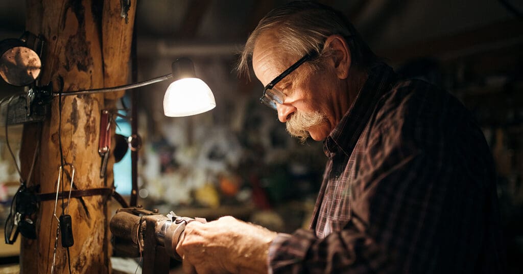 Old man worker in a workshop wearing protection goggles.