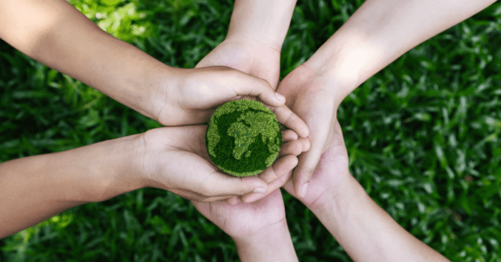 A group of hands holding a green earth.