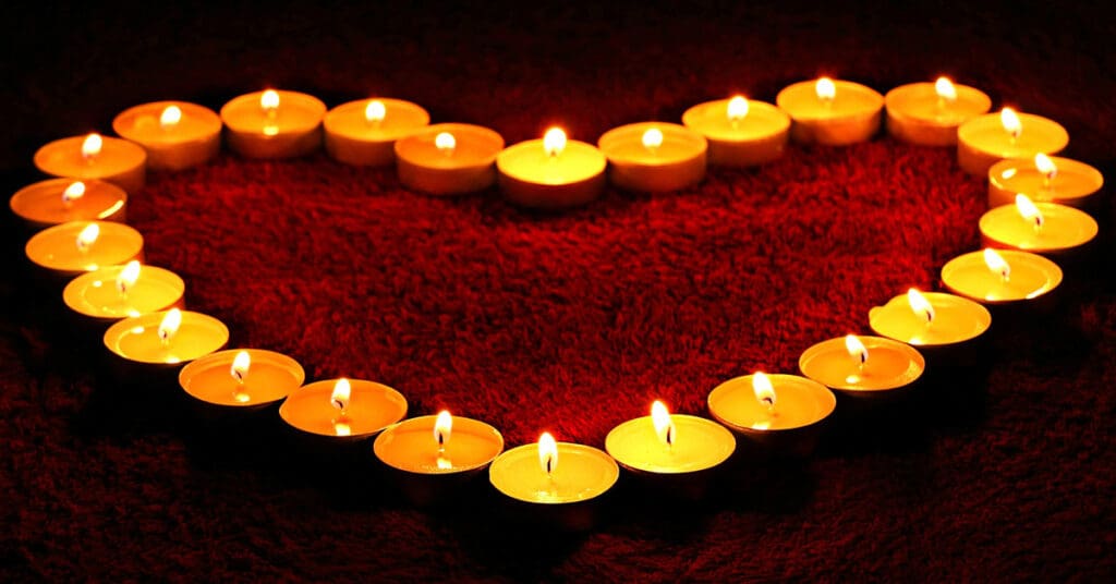 Lit tealights in the dark room shaped into a heart.
