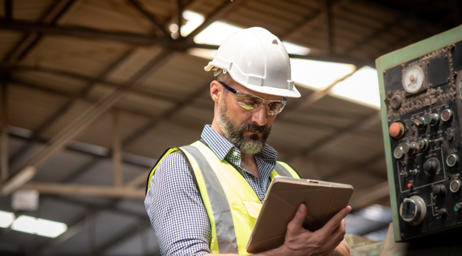 Male Engineer or Technician in Safety Uniform Working and Checking the Maintenance Information Online Data of the Machine in the Tablet.
