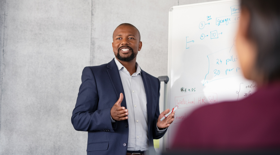 A man standing up delivering training on a whiteboard.