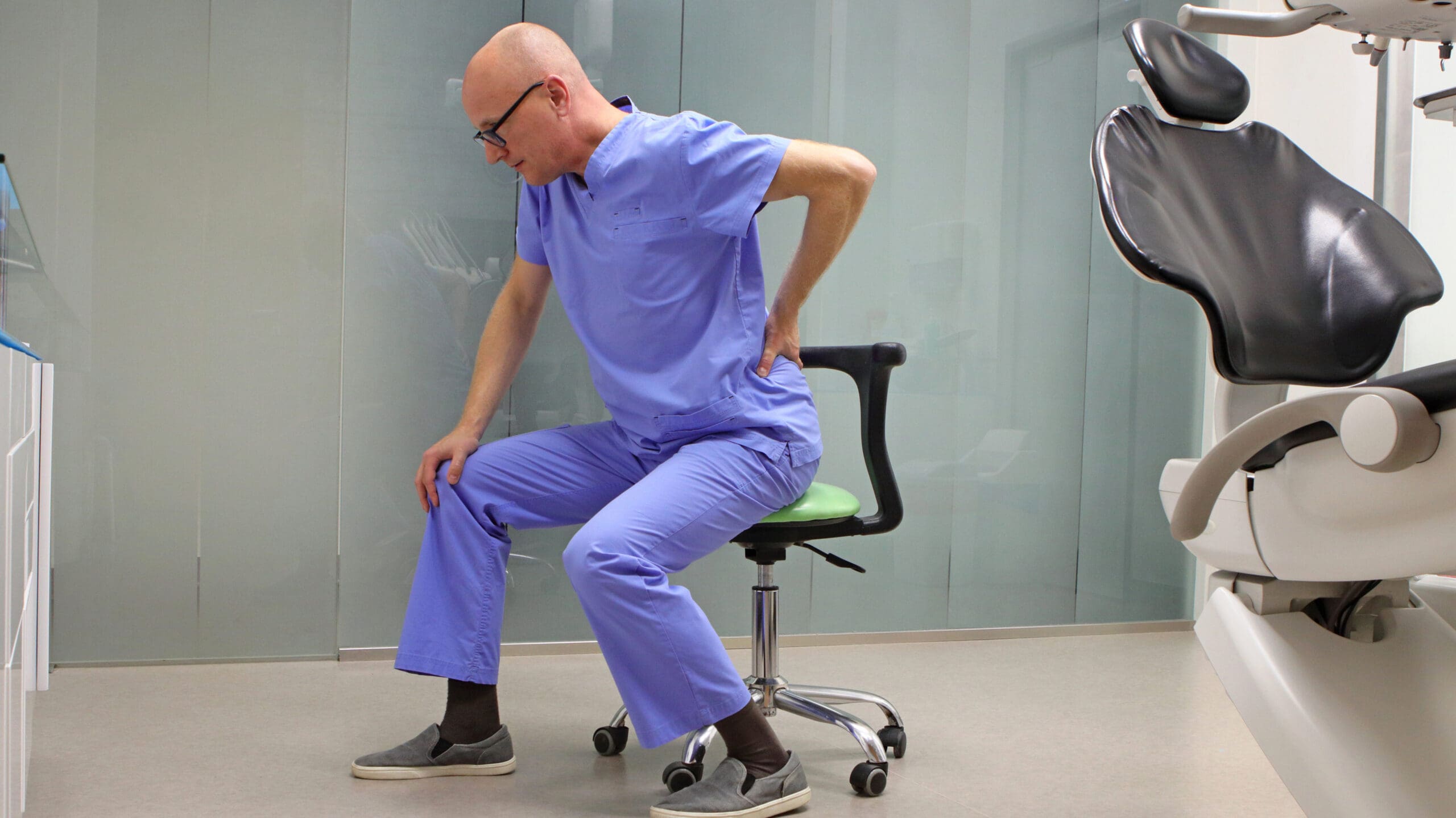 A dentist holding his back in pain. 