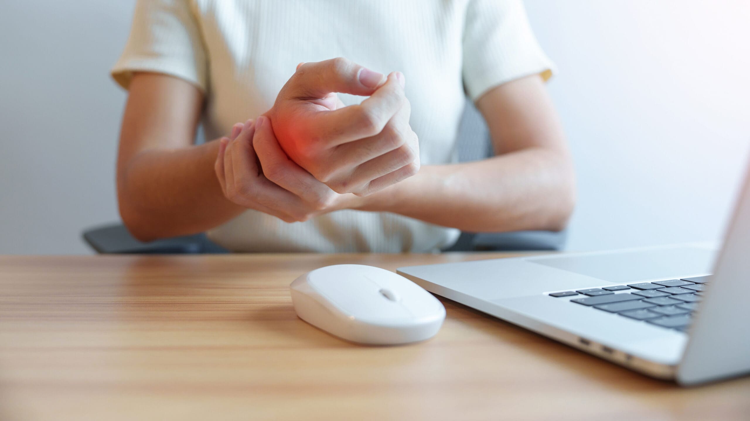 Woman holindg her wrist in pain when using mouse.