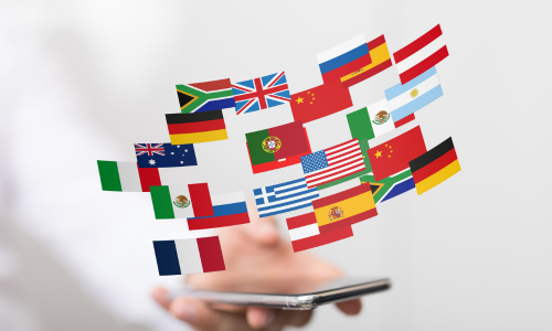 a hand holding a mobile phone with a variety of country flags hovering above.