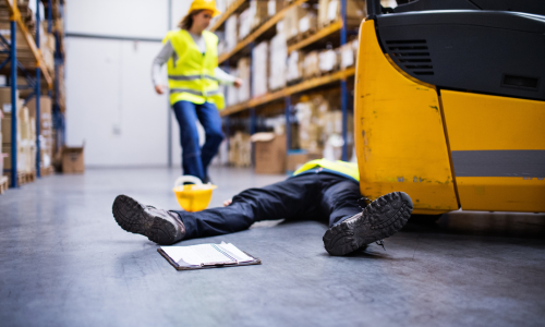a person on a floor of a warehouse after being struck by a forklift.