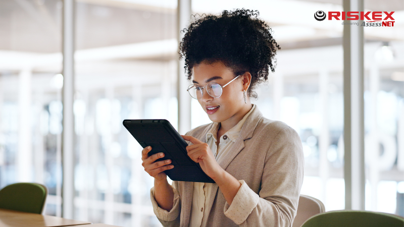 A lady sitting down in an office filling out a form on a tablet.