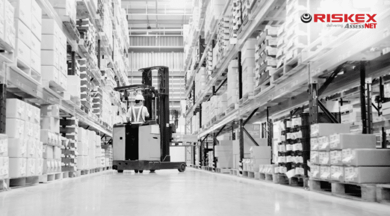 a worker on a forklift in a warehouse facing away from the camera.