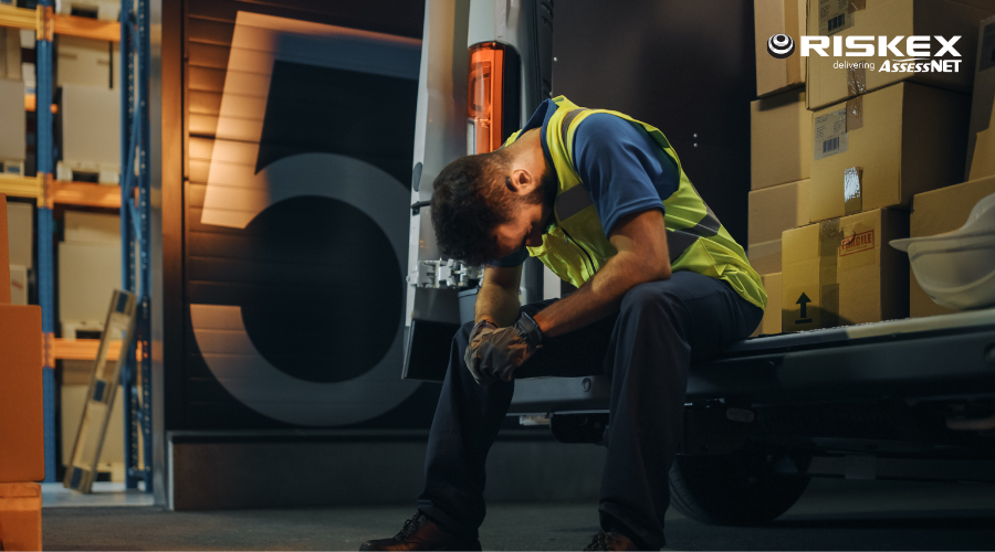 a stressed Worker Wearing Hard Hat Loads Cardboard Boxes into Delivery Truck.
