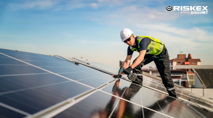 Man in PPE on a roof installing solar panels.