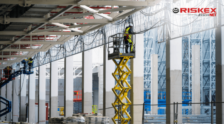 Construction workers using scissor lifts to carry out work at height inside a large industrial building.